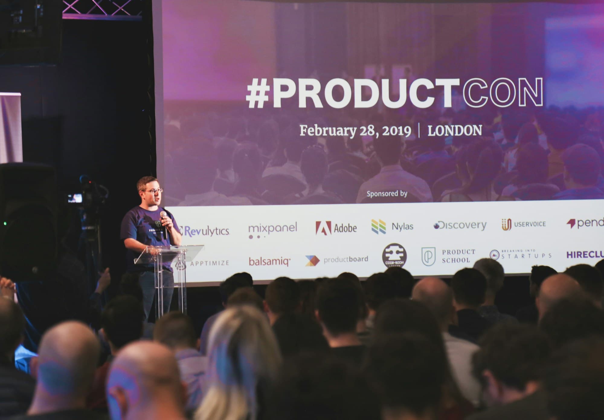 A presenter stands behind a podium during a product launch event